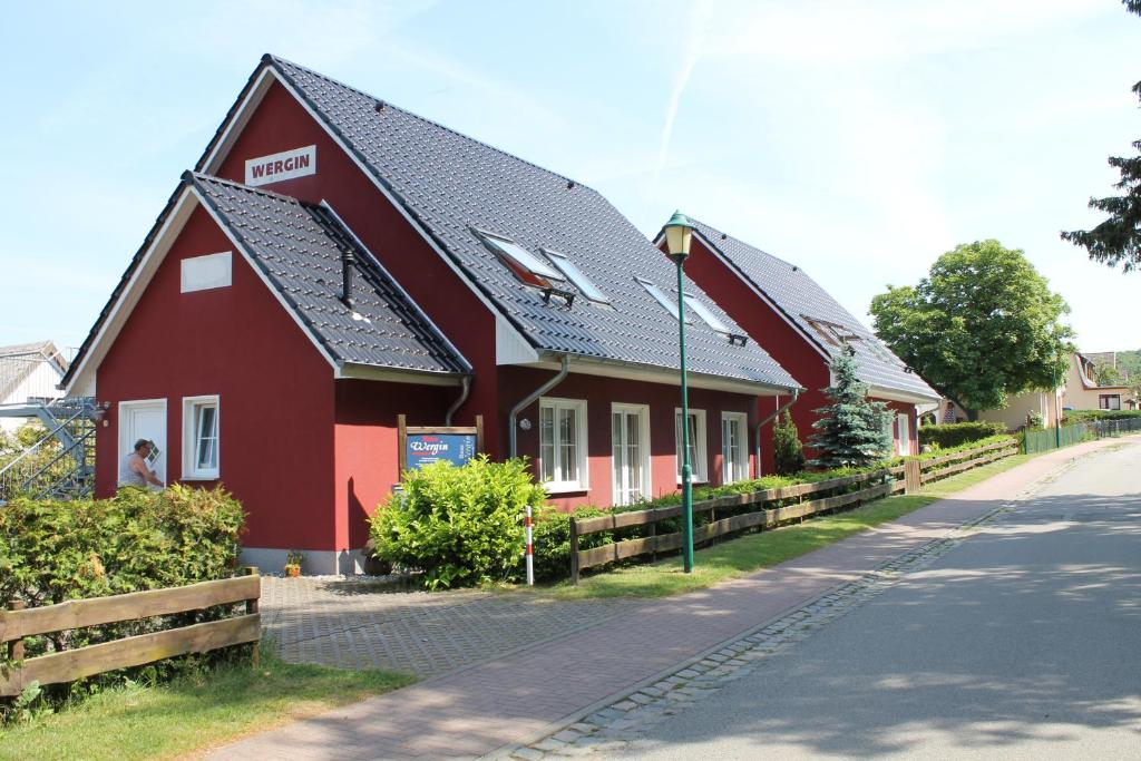 ein rotes Haus mit schwarzem Dach auf einer Straße in der Unterkunft Ferienwohnungen Wergin in Ostseebad Koserow