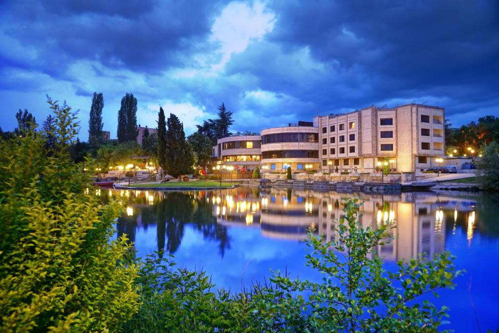 a building next to a body of water at night at Park Hotel Stara Zagora in Stara Zagora