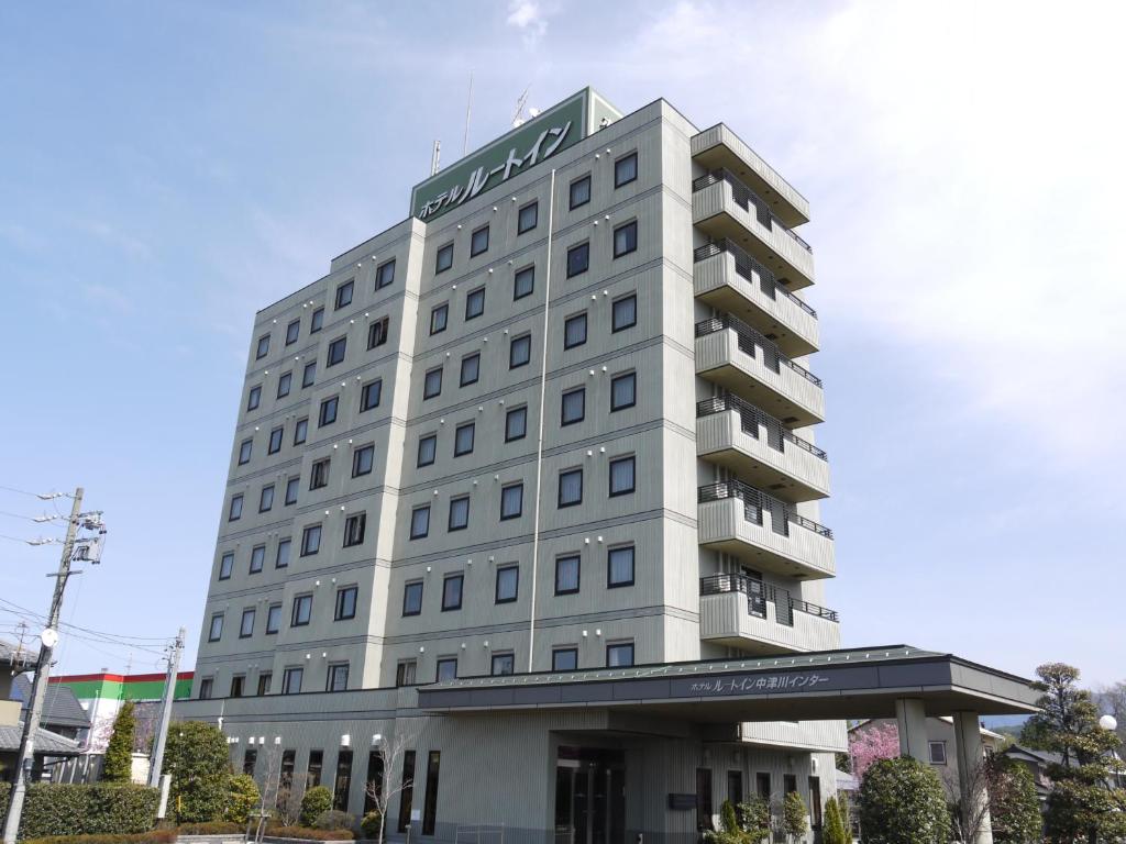 um edifício branco alto com um cartaz em Hotel Route-Inn Nakatsugawa Inter em Nakatsugawa