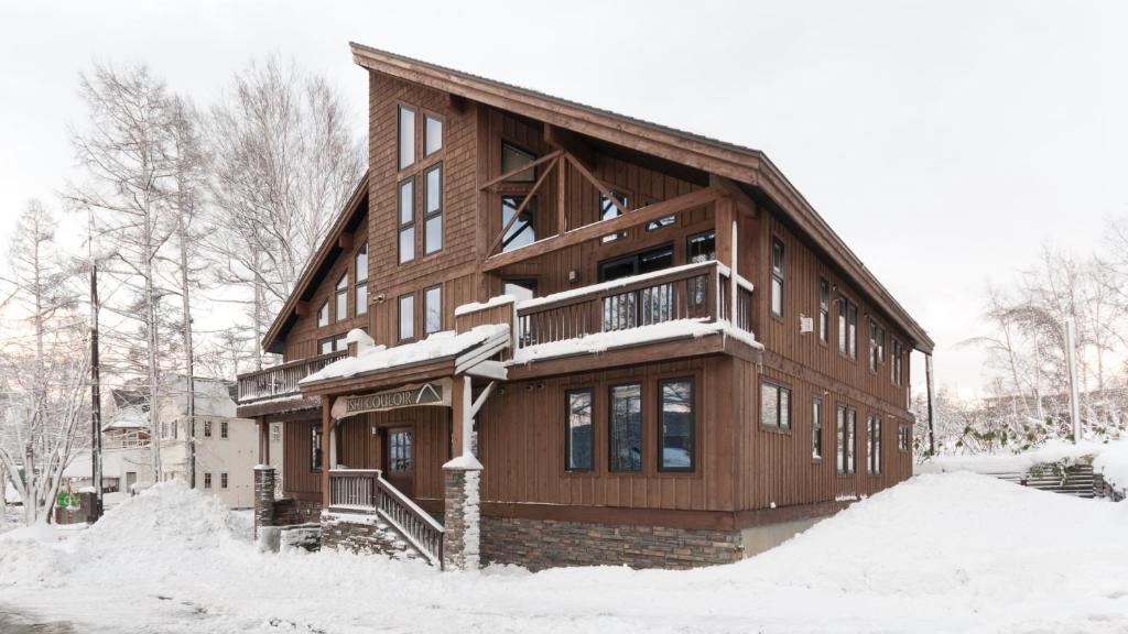 a large wooden house with a balcony in the snow at Ishi Couloir in Niseko