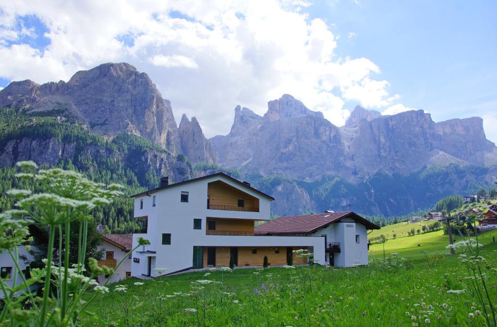 a house on a hill with mountains in the background at Alpin Relais B&B Villa Melisse in Colfosco