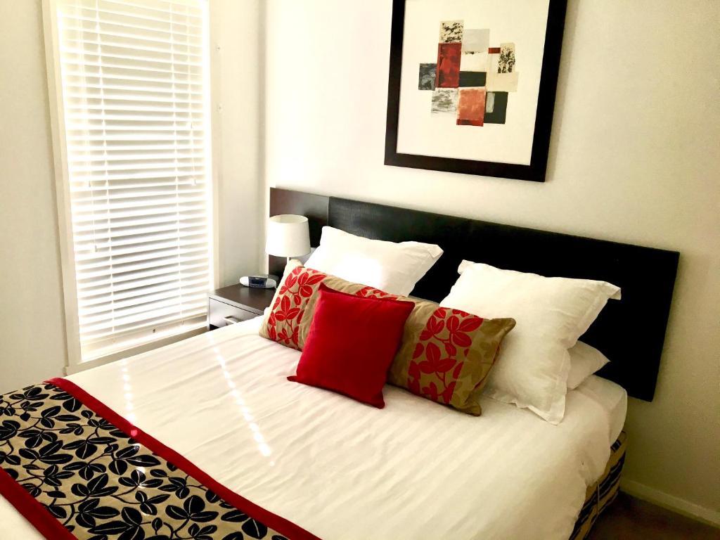 Un dormitorio con una cama con almohadas rojas y blancas. en Encore Apartments, en Bathurst