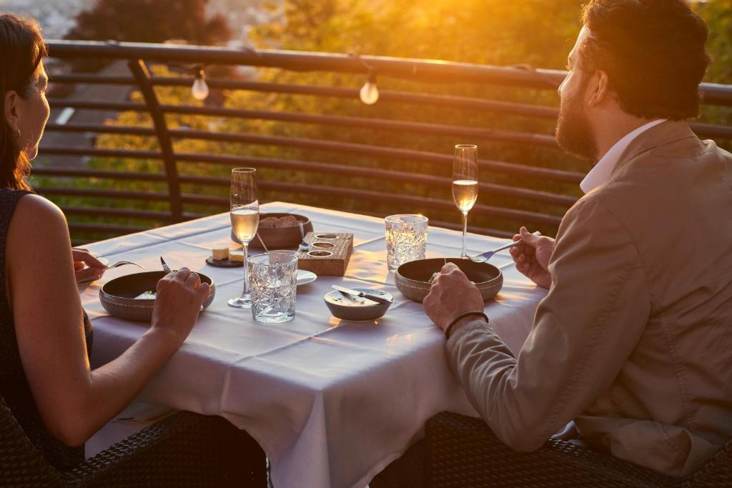 a man and woman sitting at a table with wine glasses at Sorell Hotel Rigiblick - Studios & Spa Suites in Zürich