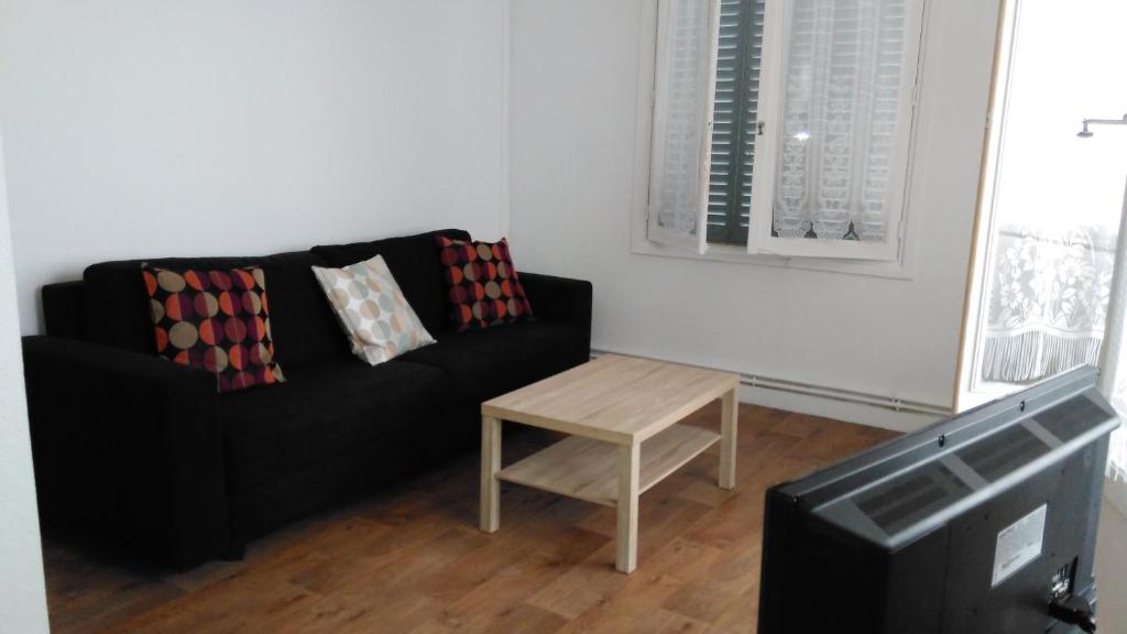 サン・テティエンヌにあるBel appartement a vivreのリビングルーム(黒いソファ、テーブル付)
