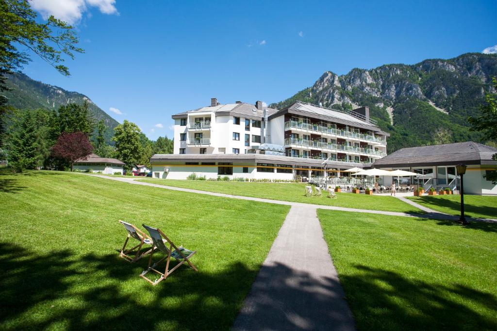 a large building on a grass field with two chairs at Parkhotel Hirschwang in Reichenau