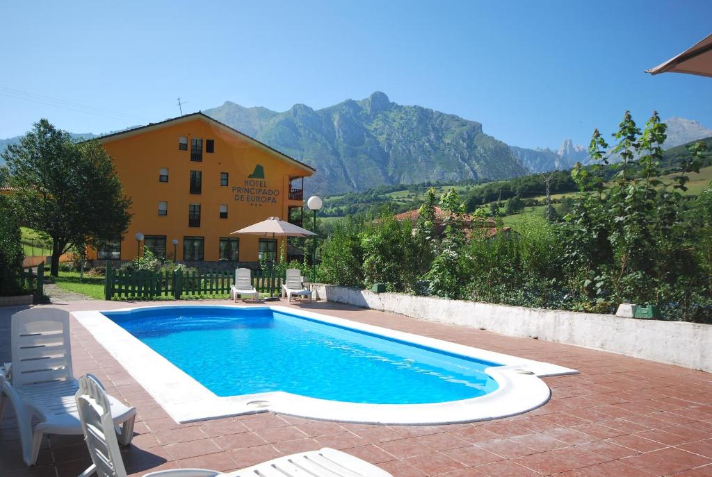 a swimming pool in front of a house with mountains at Hotel Principado De Europa in Arenas de Cabrales