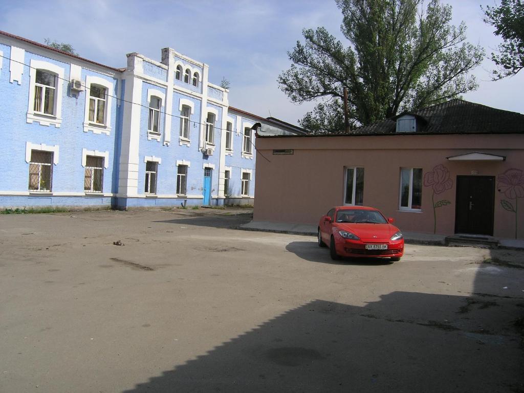 a red car parked in front of a building at Hostel Raiduzhny in Kharkiv