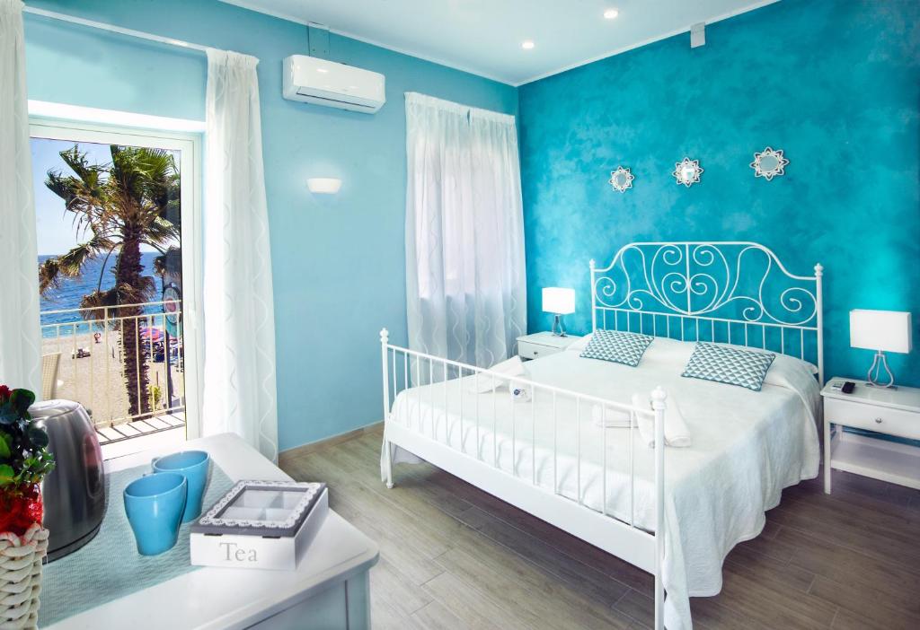 a blue bedroom with a white bed and a window at Ciao Ciao Rooms in Letojanni