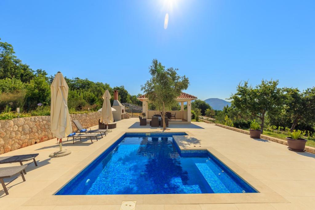 a pool with chairs and umbrellas next to a house at Hedera Estate, Villa Hedera VII in Zaton
