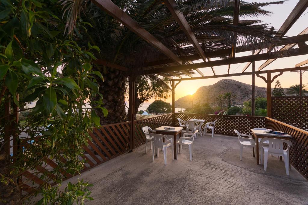 un patio con tavoli, sedie e il tramonto di Saint Nicolas Bungalows ad Arkása