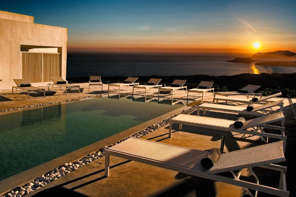 un resort con piscina con sedie e tramonto di May Seven Suites - Adults Only a Megalochori