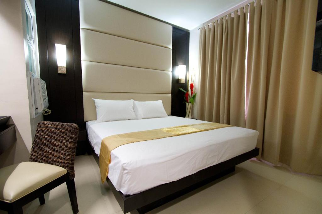 Habitación de hotel con cama y silla en Hotel Stella, en Cebú