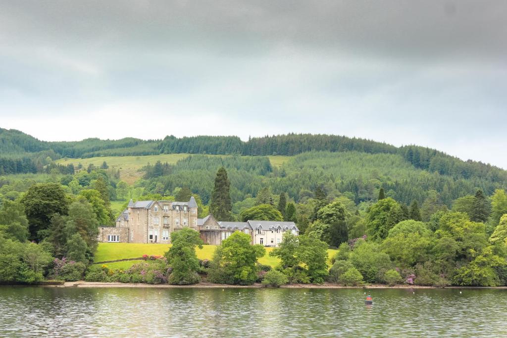a large house on the shore of a lake at Benoch Lomond Castle in Alexandria