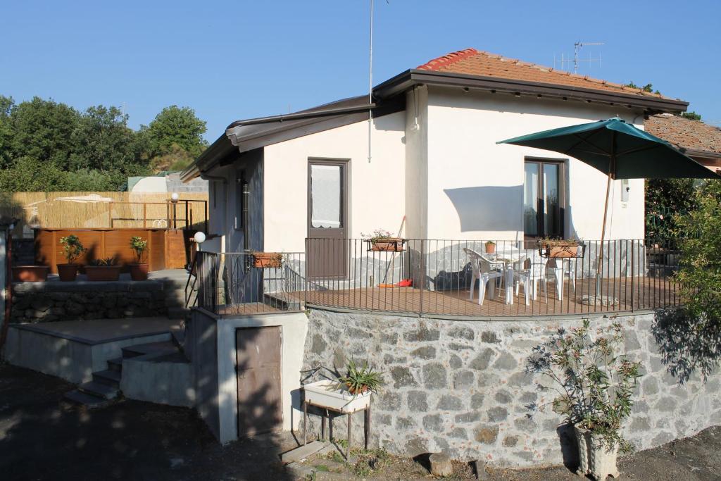 ein kleines weißes Haus mit einer Terrasse und einem Sonnenschirm in der Unterkunft Casa Vacanza Etna in Linguaglossa