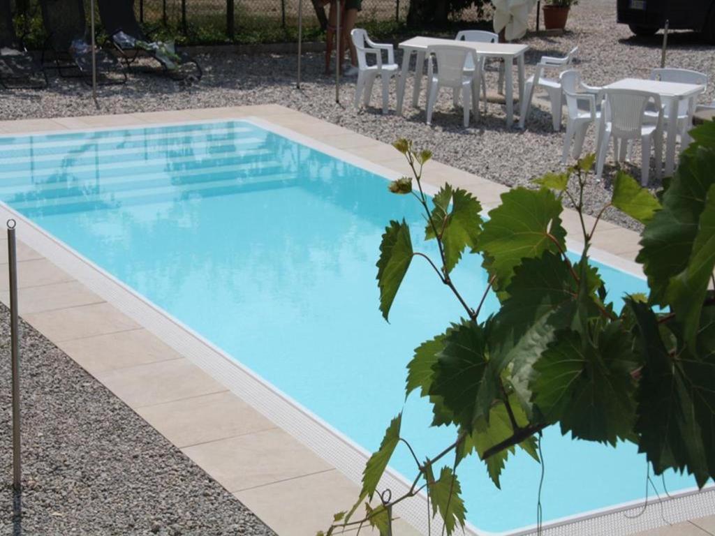 a blue swimming pool with a table and chairs at Appartamenti Gardastivo in Arco