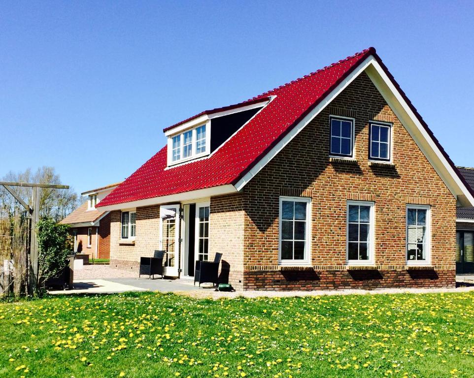 une grande maison en briques avec un toit rouge dans l'établissement Groepsaccomodatie Tzummarum, à Tzummarum