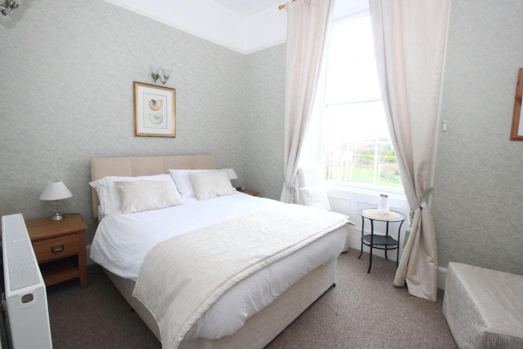 een slaapkamer met een wit bed en een raam bij The Southfield Hotel in Girvan