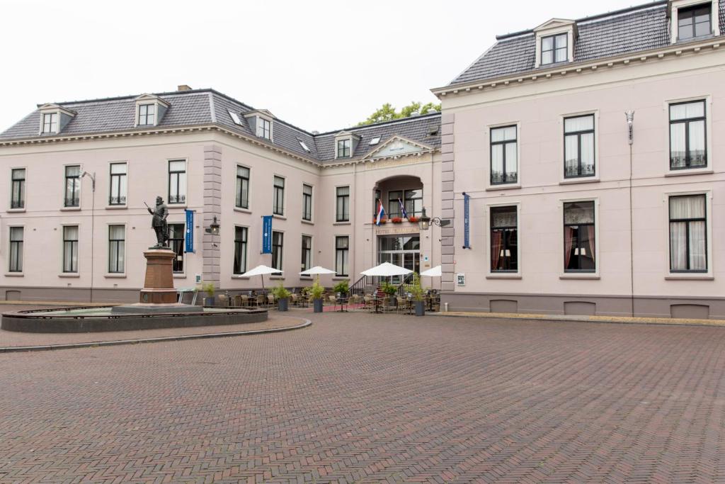 a row of white buildings with a statue in the middle at Fletcher Hotel Paleis Stadhouderlijk Hof in Leeuwarden