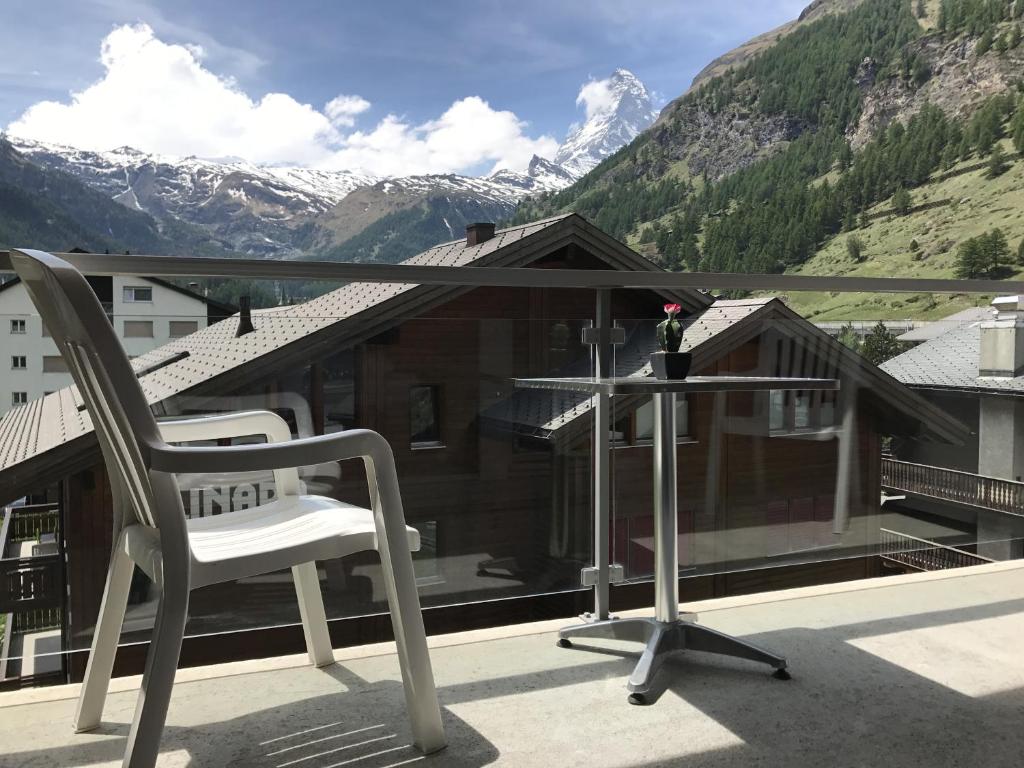 a chair on a balcony with a view of mountains at Good Value Apartments by Mountain Exposure in Zermatt