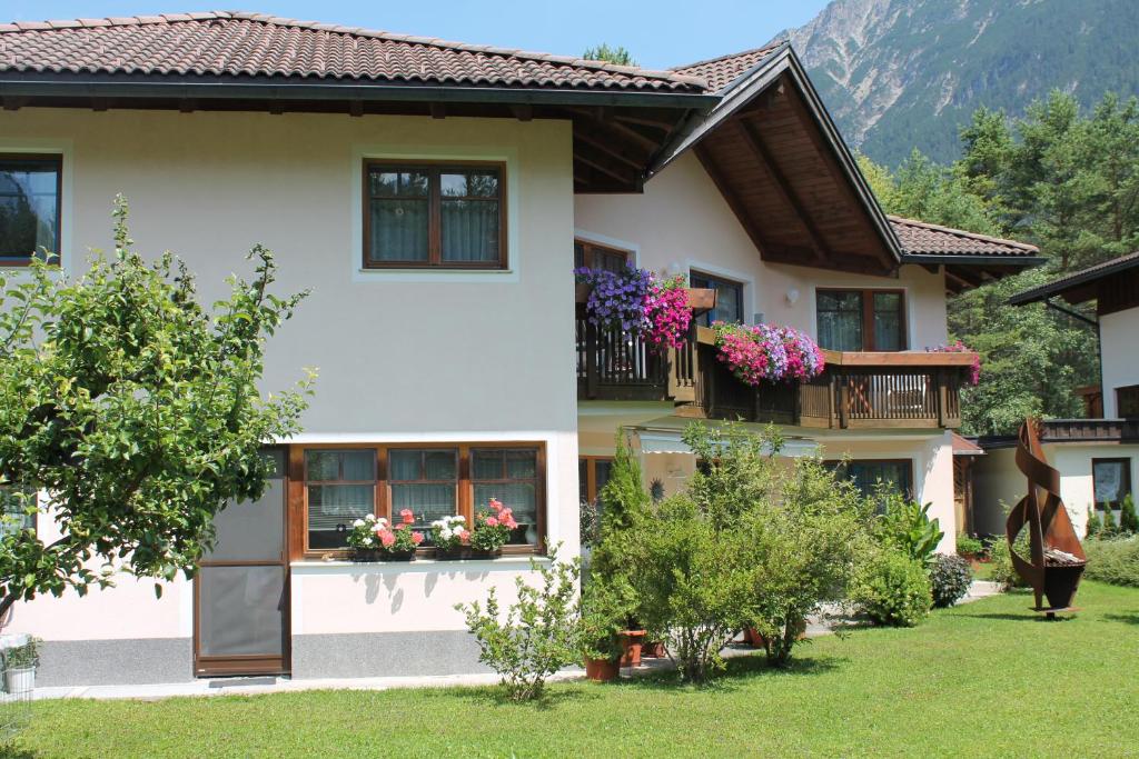 シュタンツァッハにあるApart-Alpinの庭に花を咲かせるバルコニー付きの家