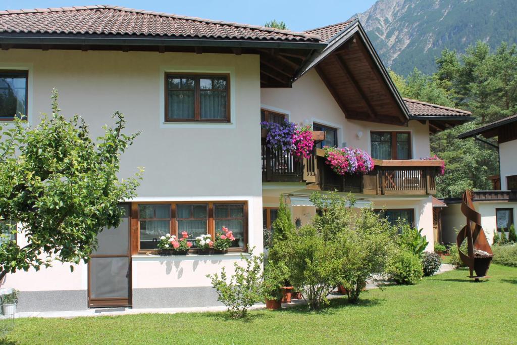 a house with a balcony with flowers in the yard at Apart-Alpin in Stanzach