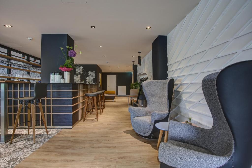 a waiting area with chairs and tables in a room at NYCE Hotel Dortmund City in Dortmund