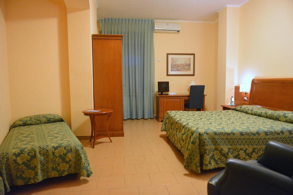 una camera d'albergo con due letti e una scrivania di Hotel Due Pini a Melfi