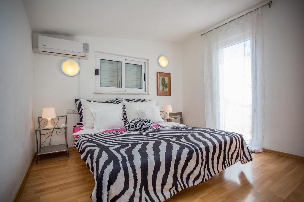 a bedroom with a bed with a zebra blanket and a window at Apartments Lux in Makarska