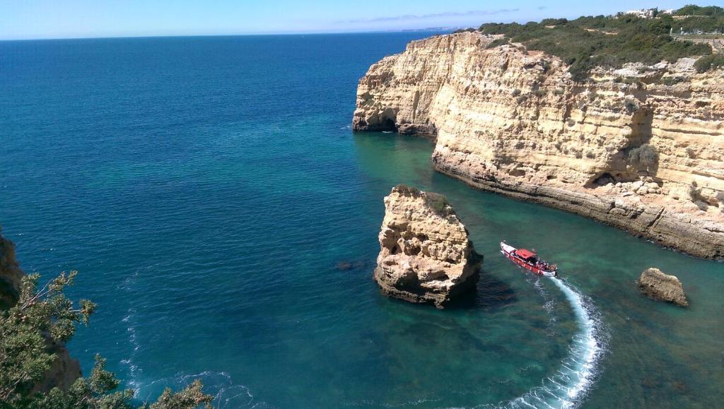 a boat in the water next to a rock formation at Pestana Palm Gardens in Carvoeiro