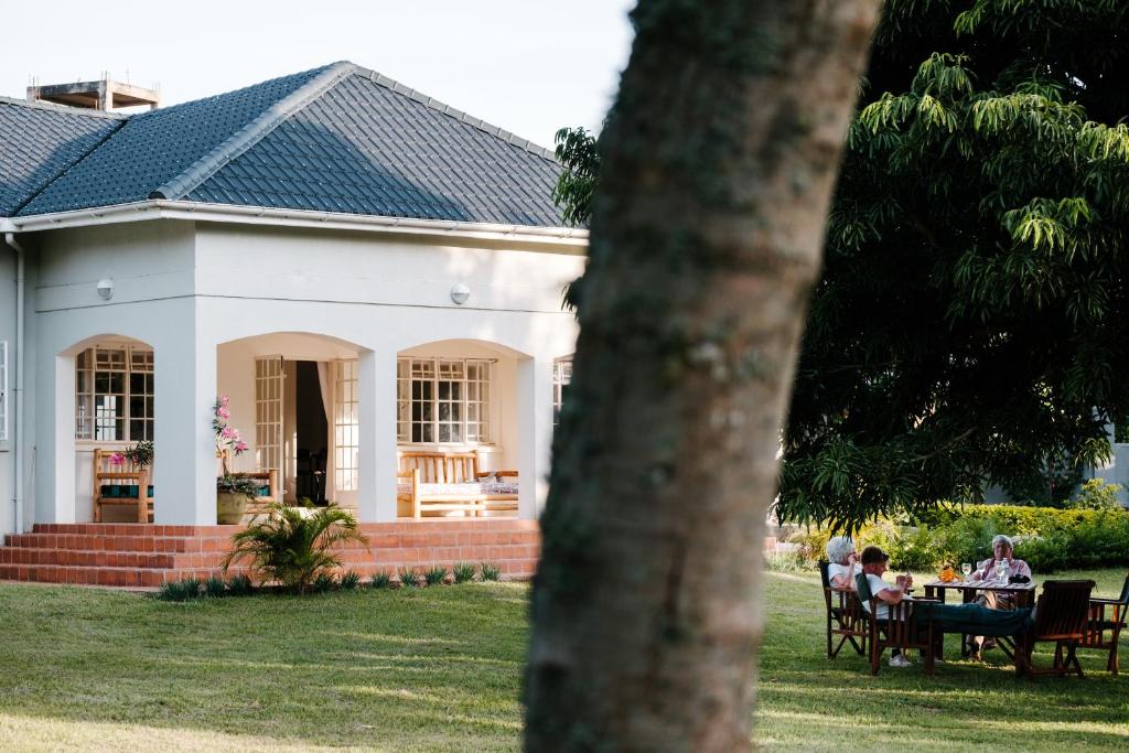 people sitting at a table in front of a white house at The Guinea Fowl in Entebbe