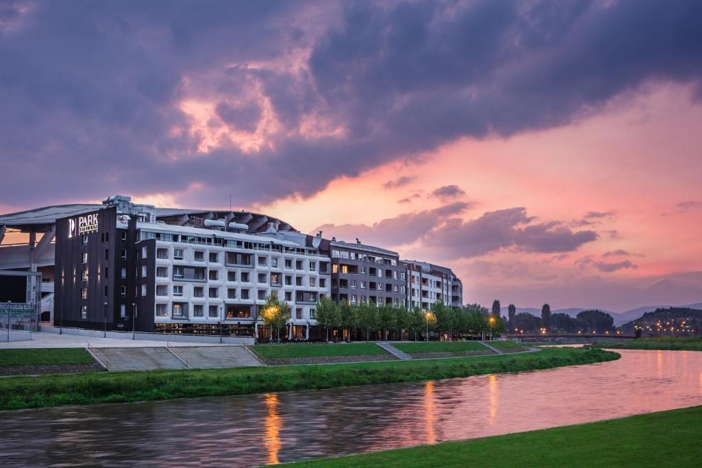 a building next to a river with a sunset at Park Hotel & Spa in Skopje