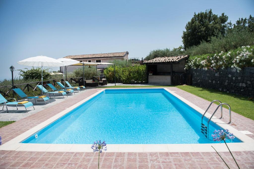 una piscina en un patio con sillas y sombrilla en Seacily Etna House, en Piedimonte Etneo