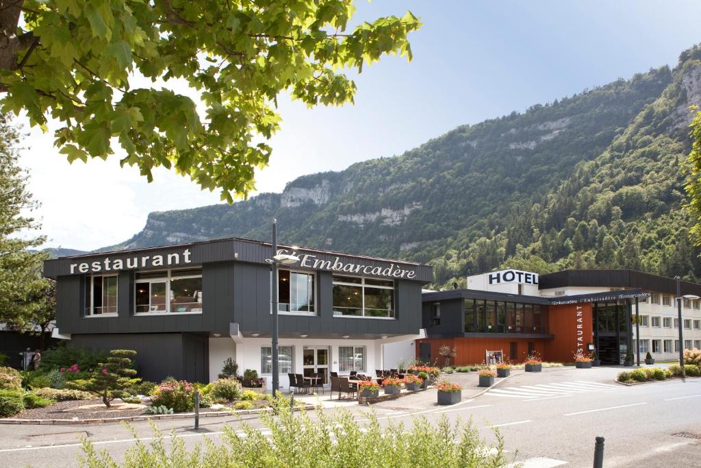 a building with a mountain in the background at Hôtel-Restaurant de l'Embarcadère in Nantua