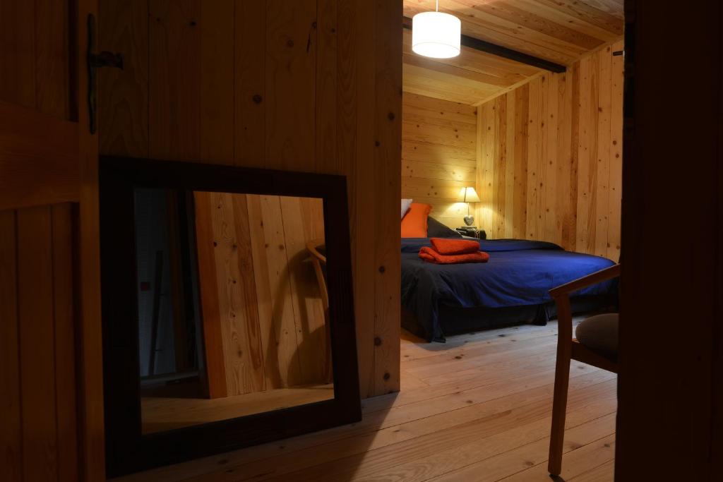 - une chambre avec un lit et un miroir dans l'établissement Le chalet de Valentine, à Ventron