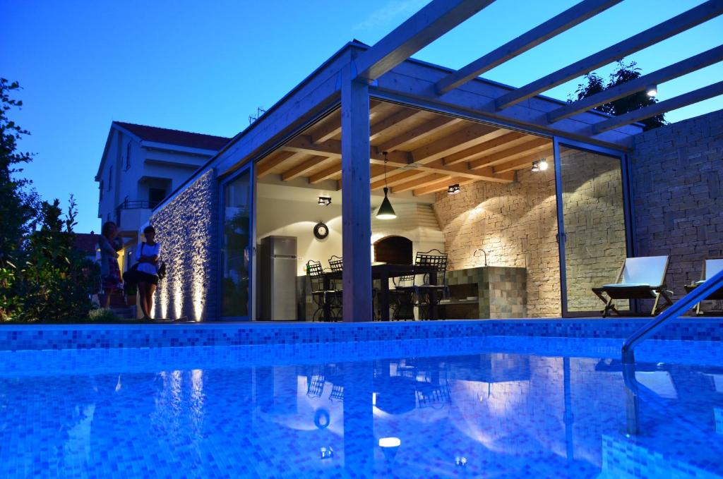 a swimming pool in front of a house at Villa Mirakul in Sukošan