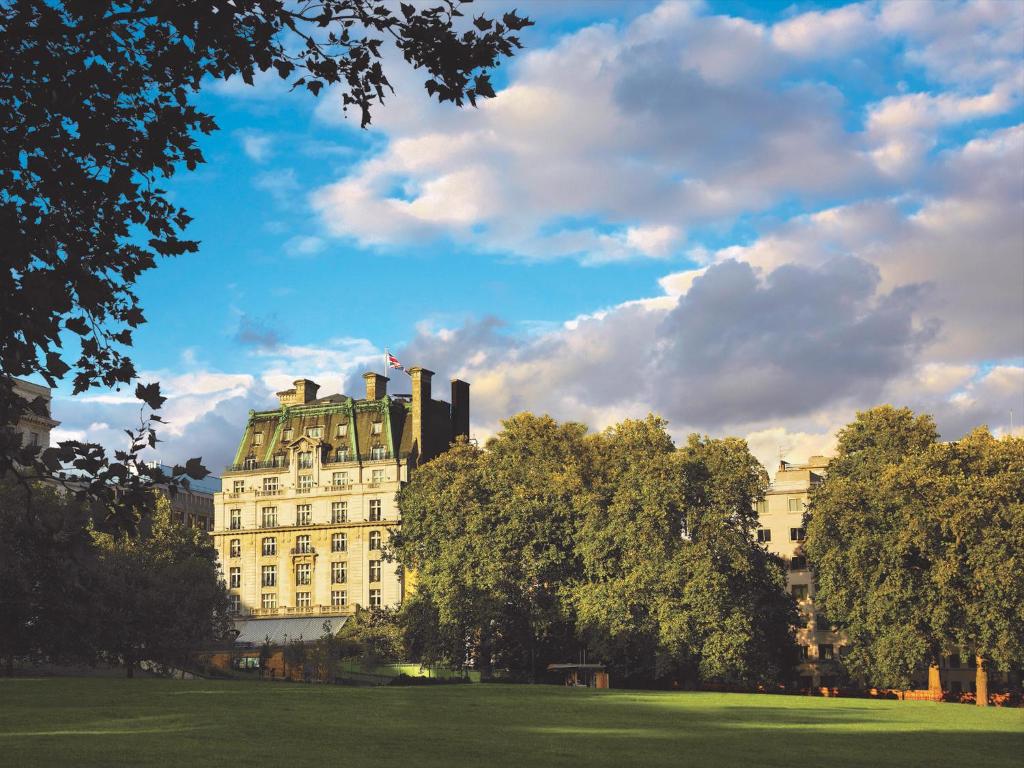 un grand bâtiment blanc dans un parc arboré dans l'établissement The Ritz London, à Londres