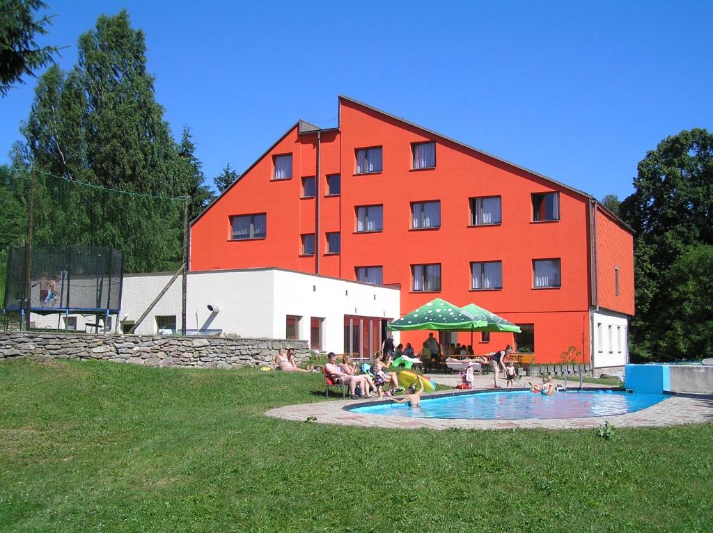 um grande edifício vermelho com pessoas sentadas à volta de uma piscina em Hotel Na Trojce em Wüst-Seibersdorf