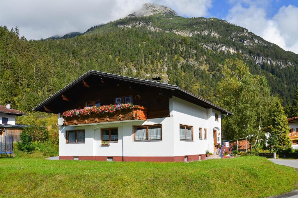 a house with flowers on the side of it with a mountain at Ferienwohnung Frauenschuh in Vorderhornbach