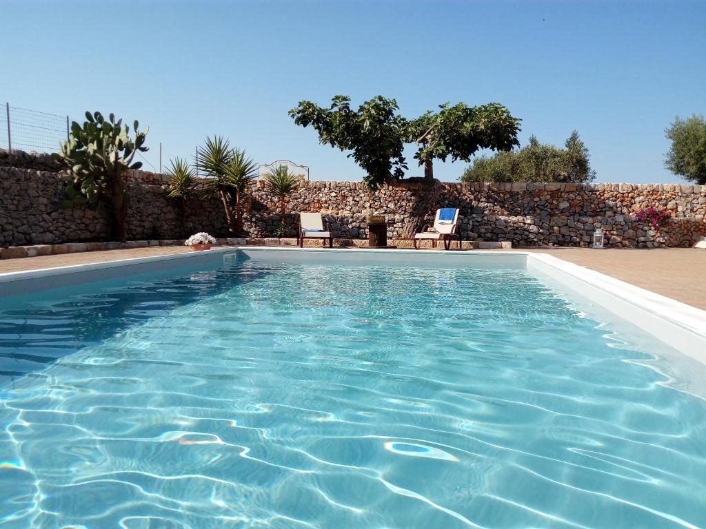 una piscina de agua azul frente a una pared en Agriturismo Masseria Alberotanza en Conversano