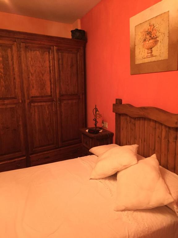 1 dormitorio con paredes rojas y 1 cama con almohadas blancas en Alojamiento Rural Los Olivos, en Arroyo Frío