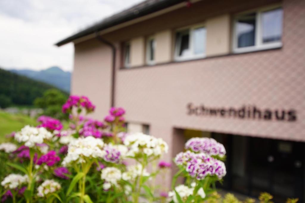 un edificio con flores púrpuras y blancas delante de él en Schwendihaus, en Amden