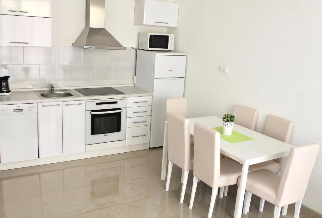 a kitchen with white cabinets and a table and chairs at Apartments Villa Milna 1 in Budva
