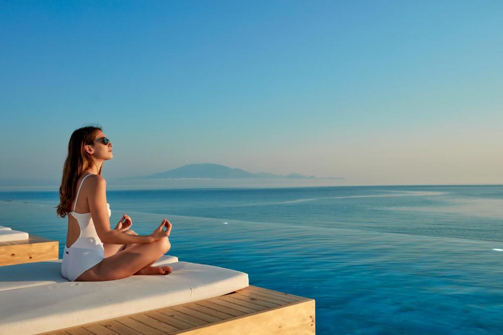 a woman sitting on the edge of a pool at Lesante Blu, a member of The Leading Hotels of the World - Adults Only in Tragaki