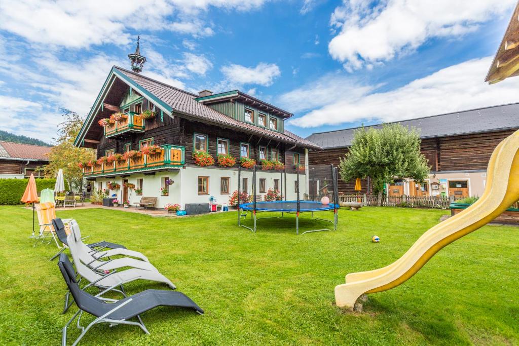ein Haus mit einem Garten mit Stühlen und einer Rutsche in der Unterkunft Bauernhof Vorderklinglhub &Landhaus Olga in Flachau