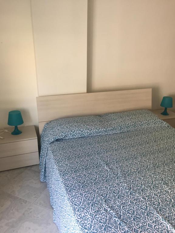 una camera da letto con un letto con un piumone blu e due lampade di B&B La Barcaccia a Tortora