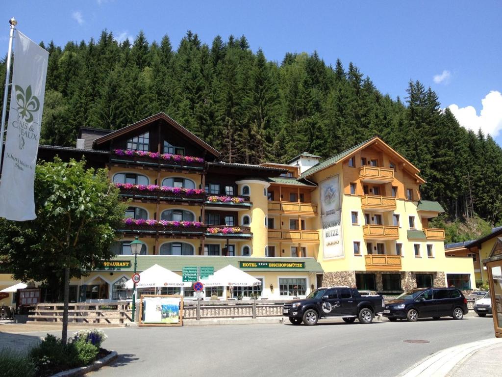 a large building with cars parked in a parking lot at Hotel Bischofsmütze in Filzmoos