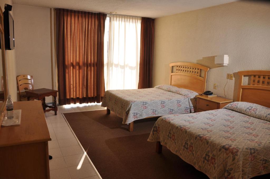 Habitación de hotel con 2 camas y ventana en Hotel El Monte en Salamanca