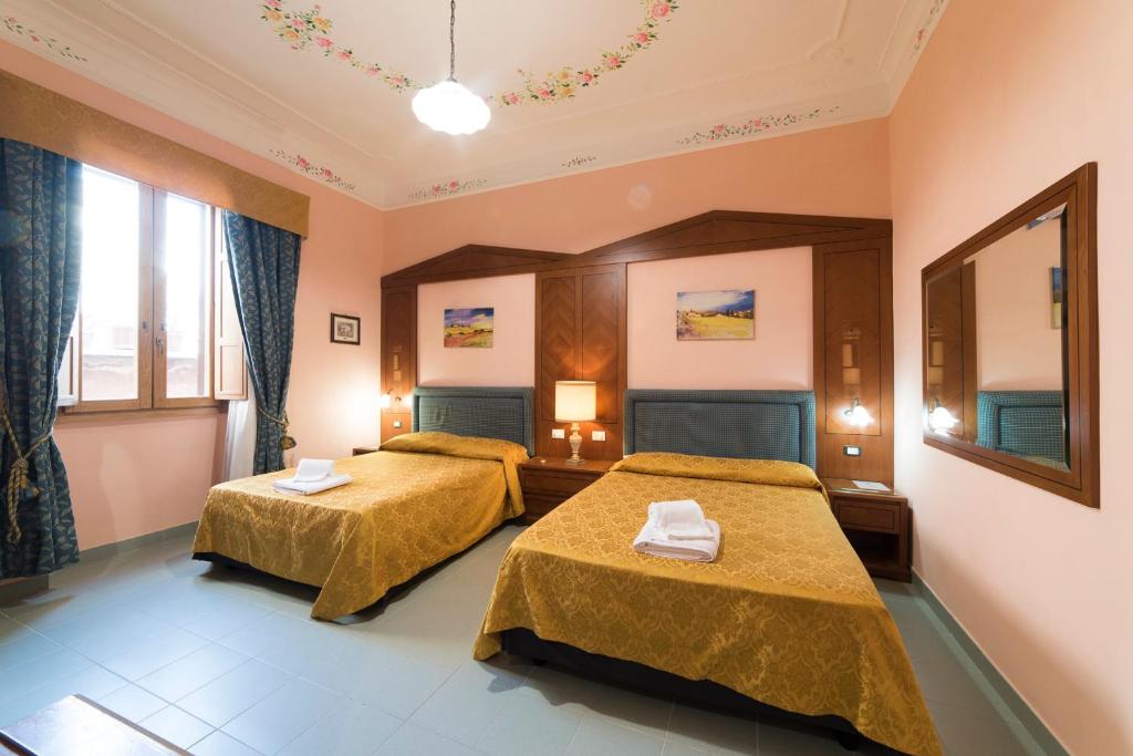 een hotelkamer met 2 bedden en een spiegel bij Al Seminario in Tivoli