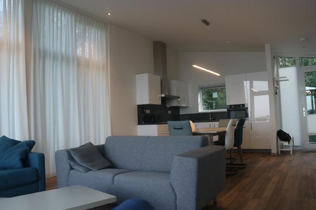 a living room with a blue couch and a table at watervilla paterswoldsemeer in Eelderwolde