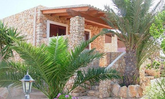 uma casa com uma palmeira em frente em Residence Punta Sottile A 2 passi dalla spiaggia di cala francese Lampedusa em Lampedusa